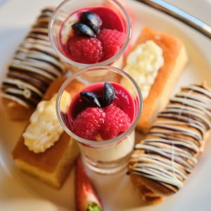 homemade eclairs and other desserts on the top tier of an afternoon tea stand