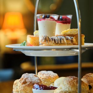 scones and a selection of desserts on the top 2 tiers of an afternoon tea cake stand