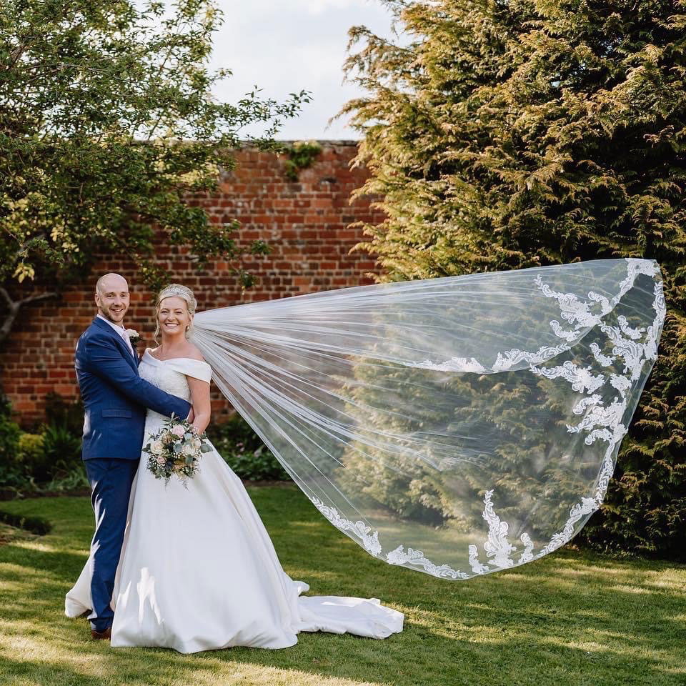 Bride and groom in the garden with the brides veil blowing in the wind