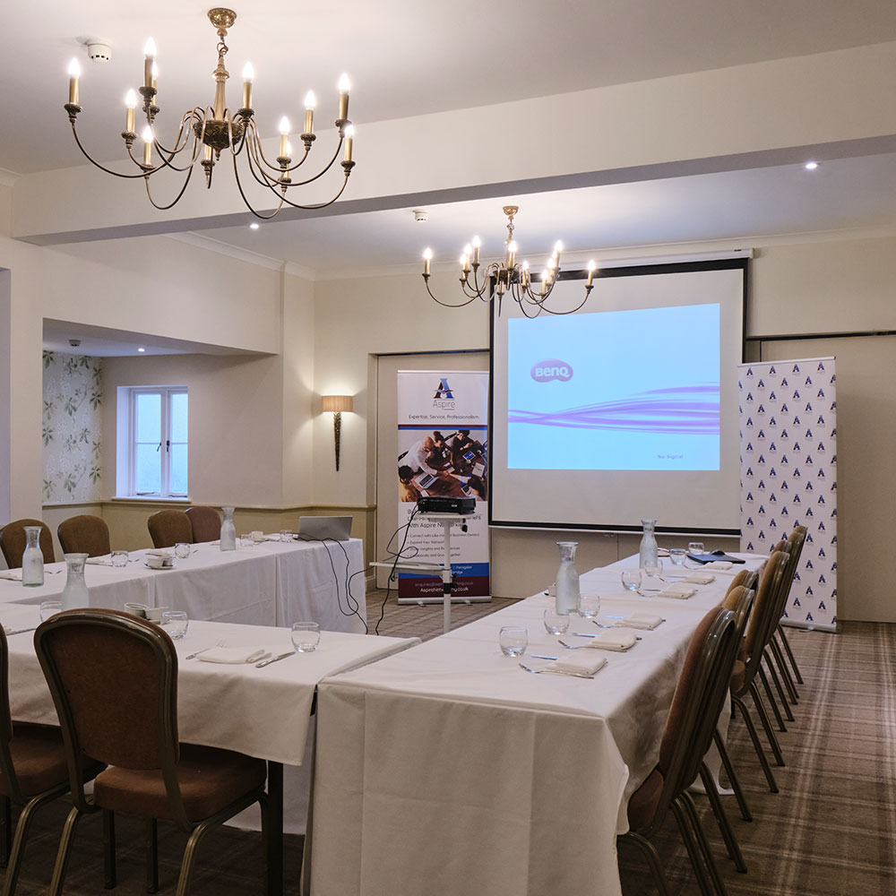 Tables set up for a presentation facing the big screen in the Stratton suite