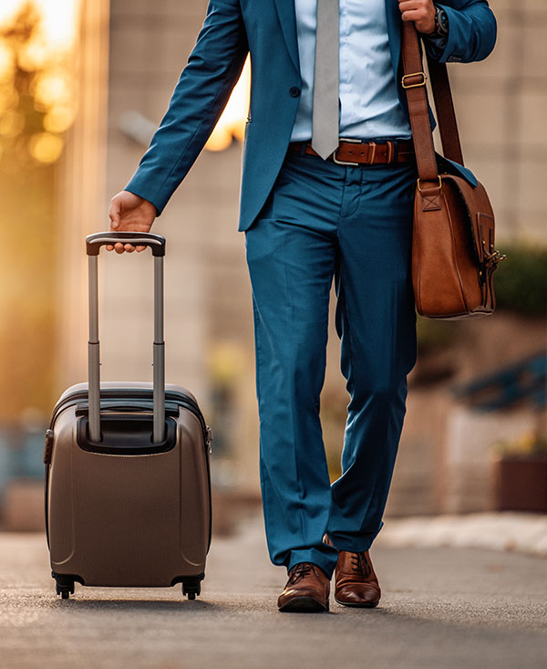 Business man in a blue suit with a suitcase walking down a street