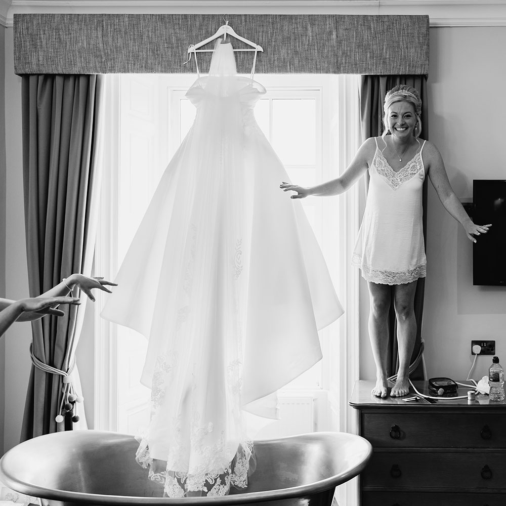 Bride stood on a table in the bridal suite next to her dress