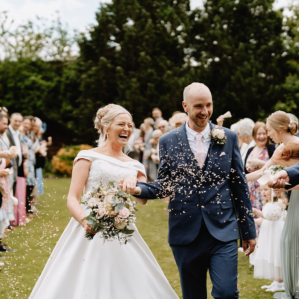 Bride and groom walking through guests that are throwing confetti