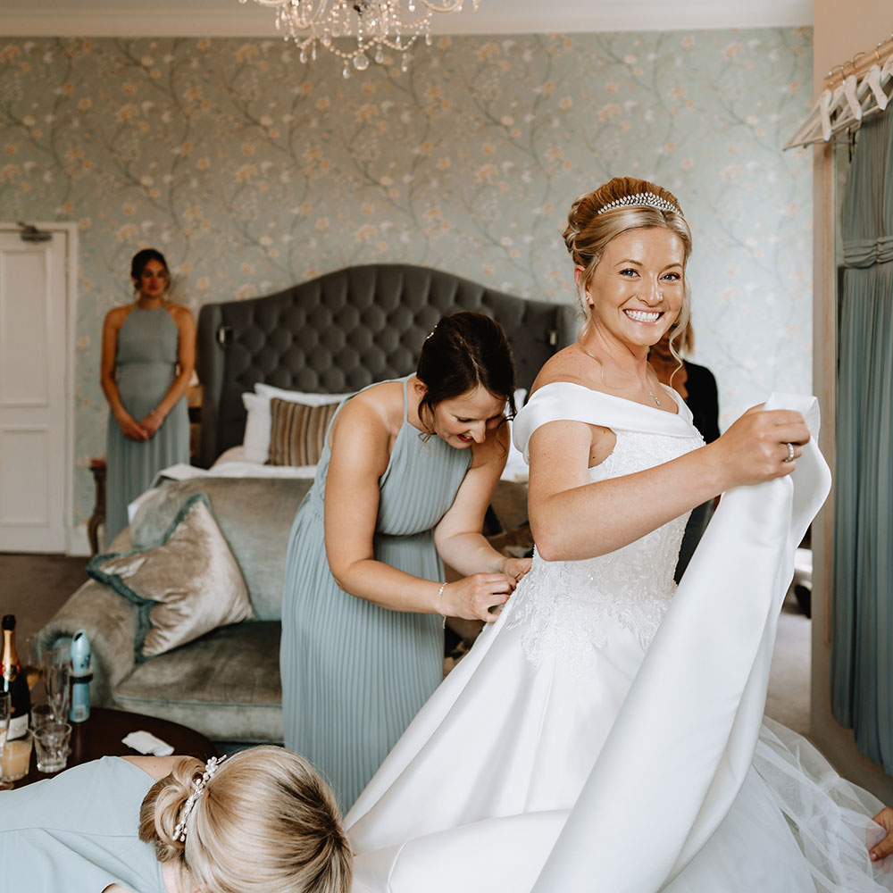 Bride having her dress sorted by her bridesmaids