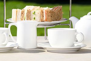 sandwiches, cups and a tea pot in the garden