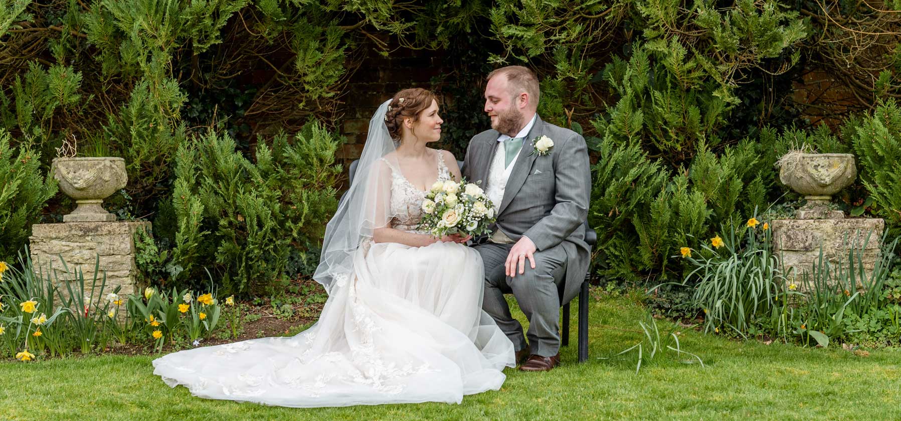 Bride and groom sat in the garden surrounded by daffodils