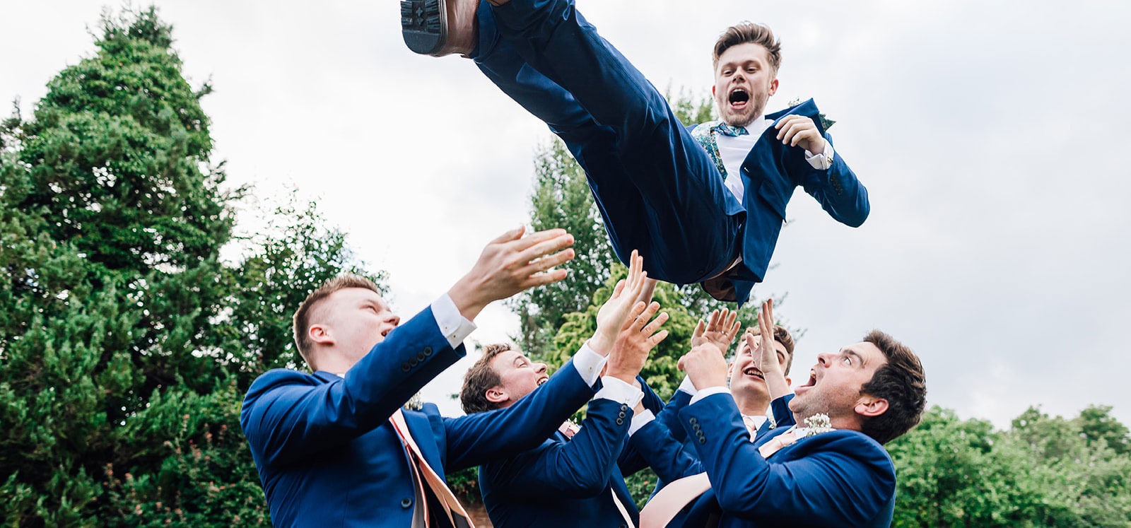 Groom getting thrown into the air by his groomsmen