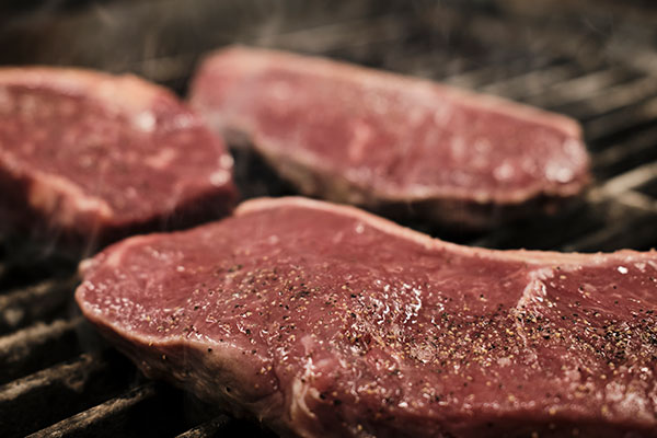 Raw steaks on a grill ready to be cooked