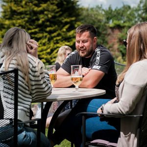 A group of people having a drink at a table in the sunshine