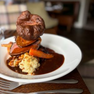 Plate of roast beef Sunday lunch with seasonal veg, Yorkshire pudding and gravy