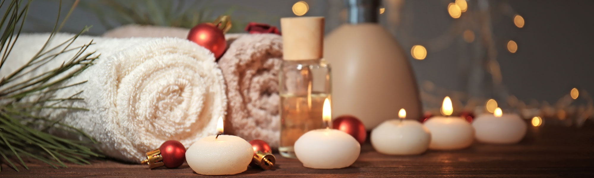 Close up of tea lights, baubles, fairy lights next to rolled up towels in a spa