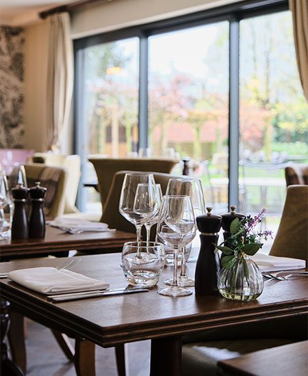 Restaurant table laid with water and wine glasses in front of the patio doors