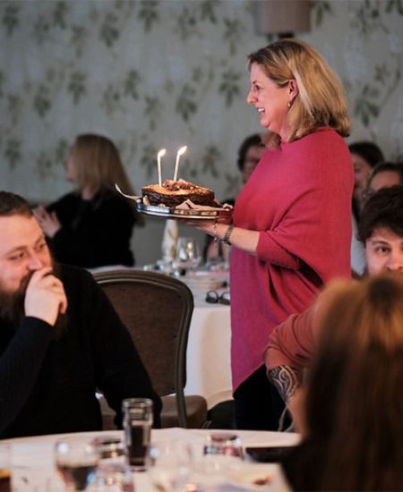 Woman carrying a birthday cake through the Stratton suite