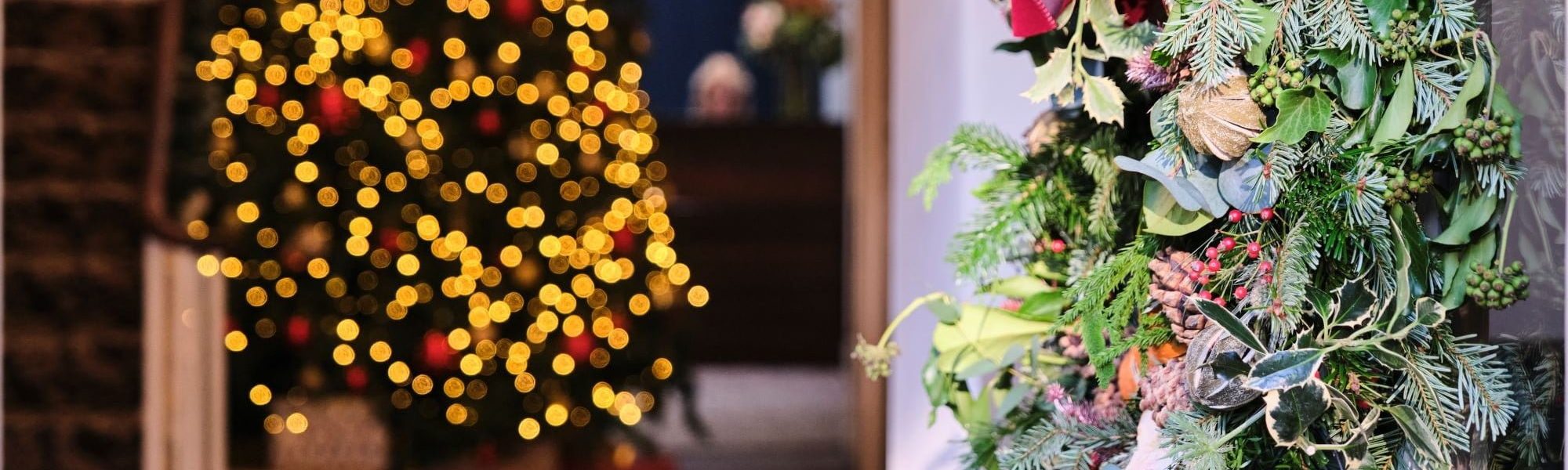 Wreath on the open door with a view through to the lit up Christmas tree