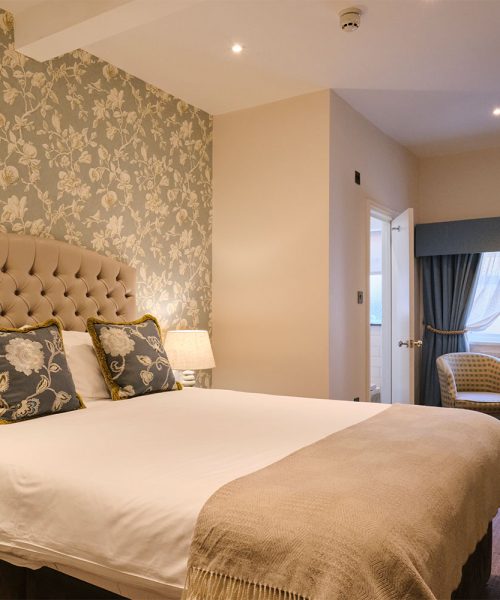 View of a double bed, desk and chair in a compact double room