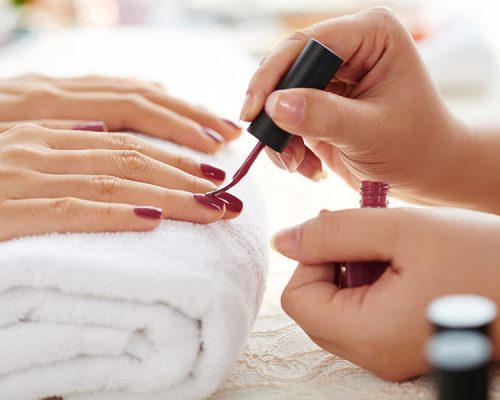 Nail appointment painting a clients nails with red nail polish